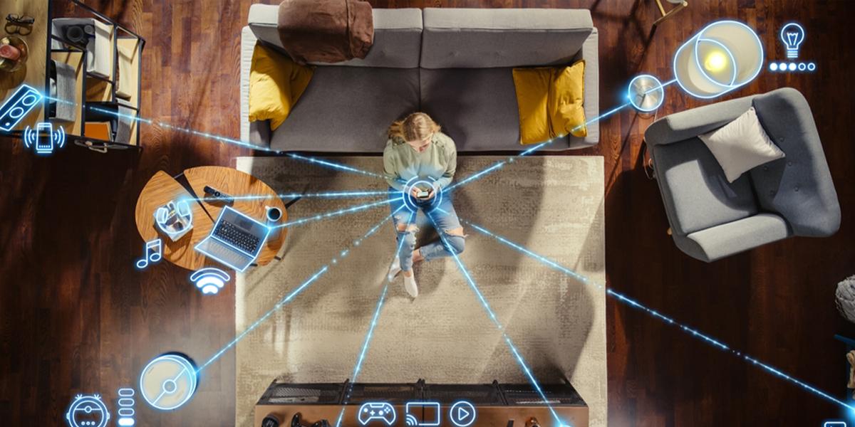 Donna seduta sul divano in salotto che controlla dallo smartphone i dispositivi smart connessi, rappresentati da icone digitali