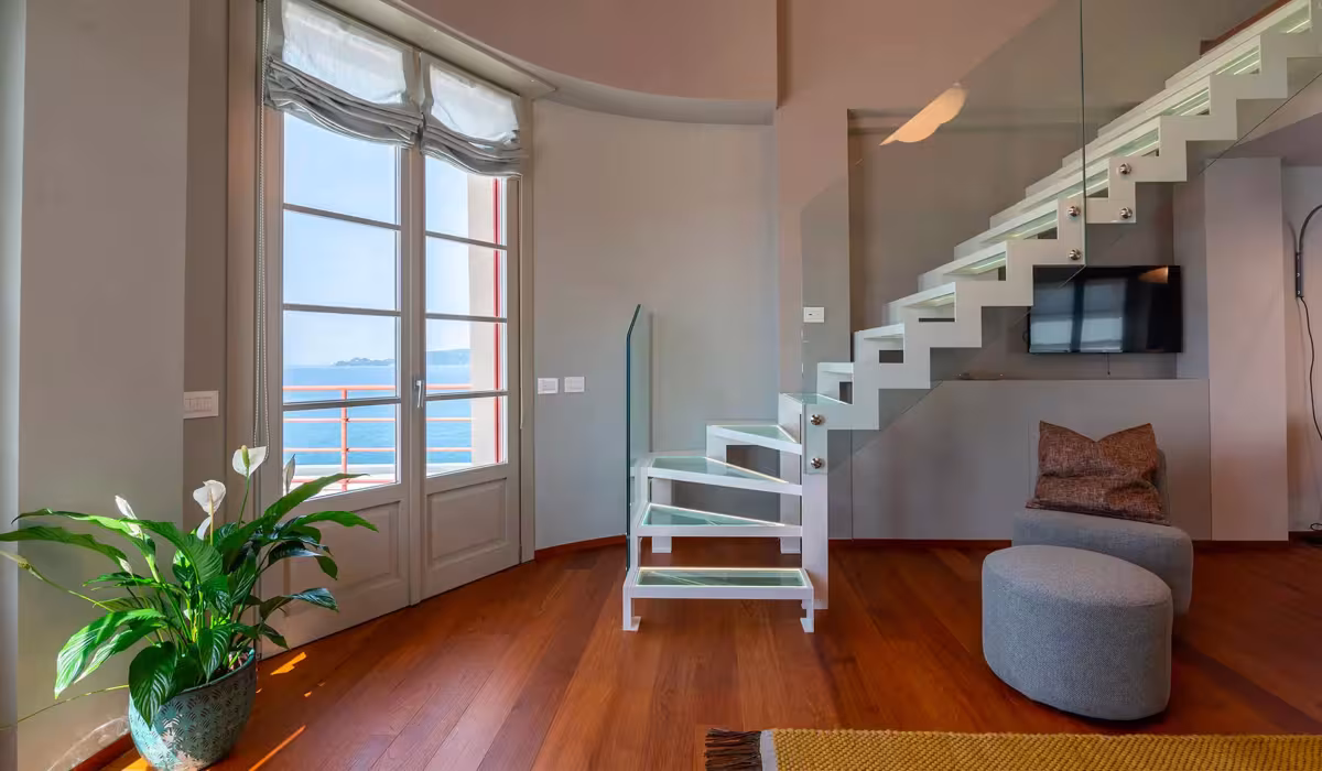 Interno dell’hotel di design Torre Fara con scala moderna in vetro, vista panoramica sul mare e placche Livinglight Bticino