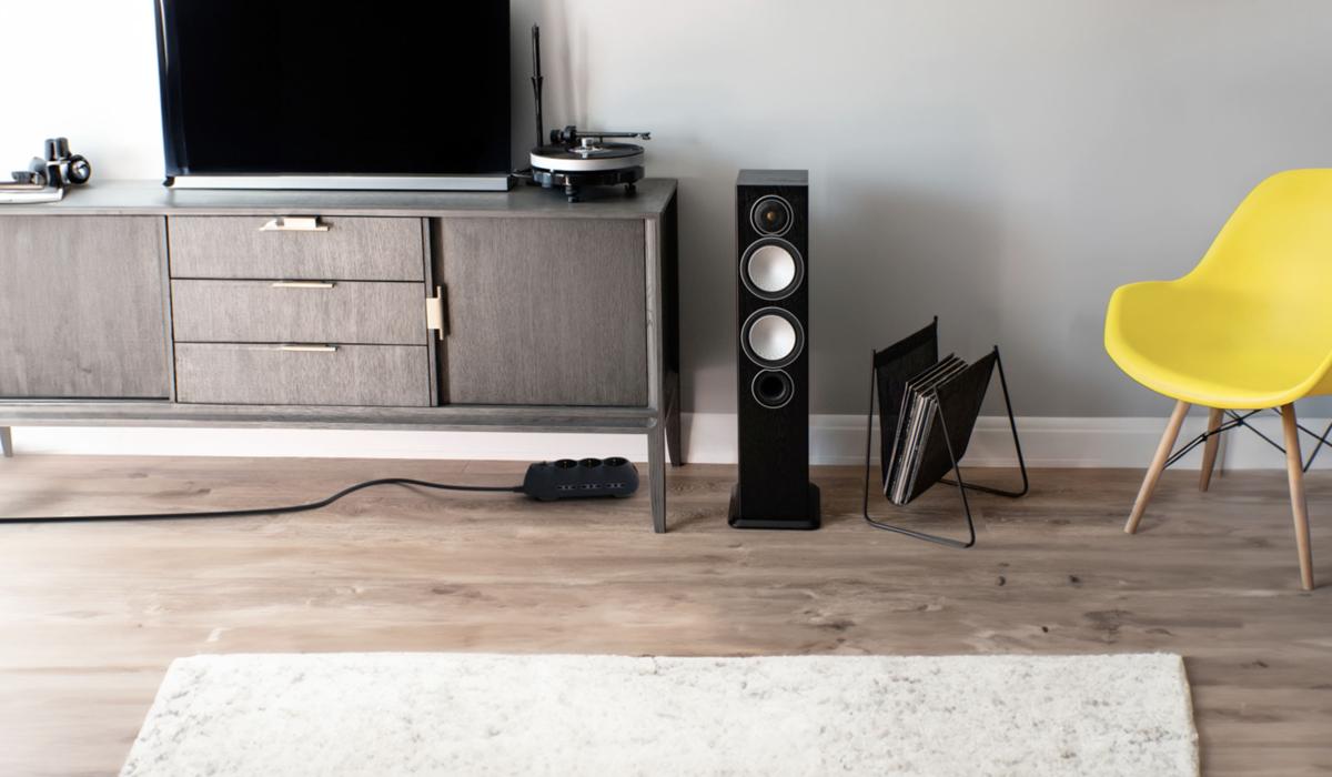 Multipresa Slot di BTicino nera a terra sotto un mobile TV in soggiorno moderno, con cavo collegato e speaker accanto
