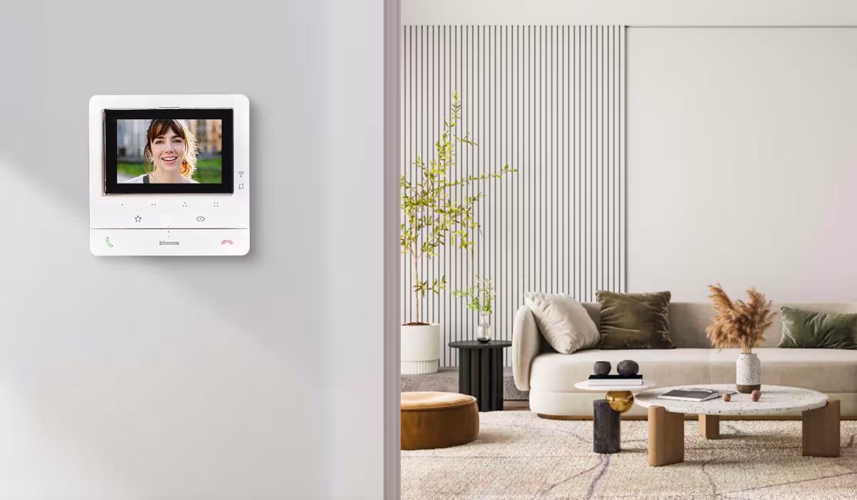 Videocitofono connesso Classe 100X Smart BTicino a parete con schermo acceso in un soggiorno moderno e luminoso