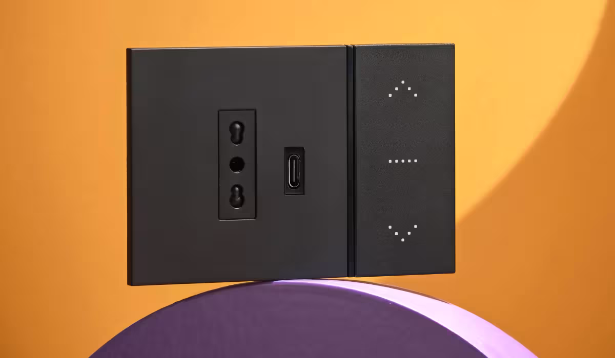 Placca di comando Living NOW BTicino con modulo USB-C integrato e comandi touch, in primo piano su sfondo arancione