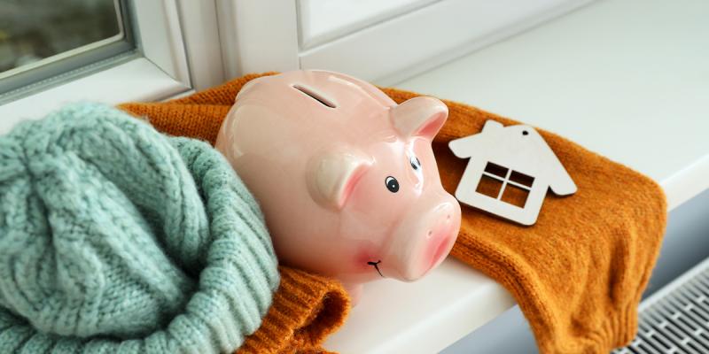 Salvadanaio e maglioni accanto a un termosifone, simbolo del risparmio sui consumi di gas