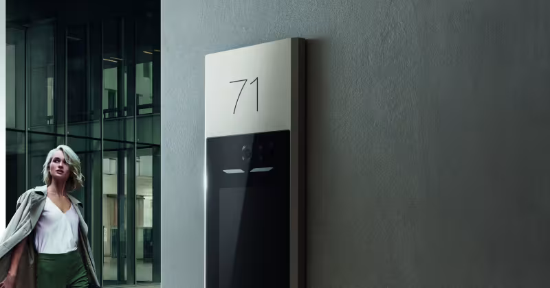 Ragazza che passeggia vicino a un ingresso condominiale, con il videocitofono Linea 5000 with Netatmo di BTicino in vista