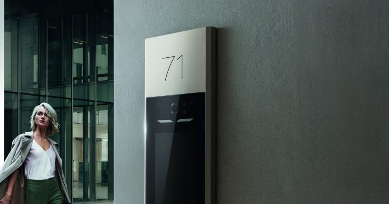 Ragazza che passeggia vicino a un ingresso condominiale, con il videocitofono Linea 5000 with Netatmo di BTicino in vista