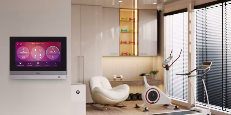Pannello touch per la gestione della domotica installato a parete, con vista sulla palestra di casa