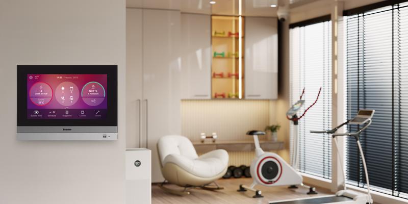 Pannello touch per la gestione della domotica installato a parete, con vista sulla palestra di casa