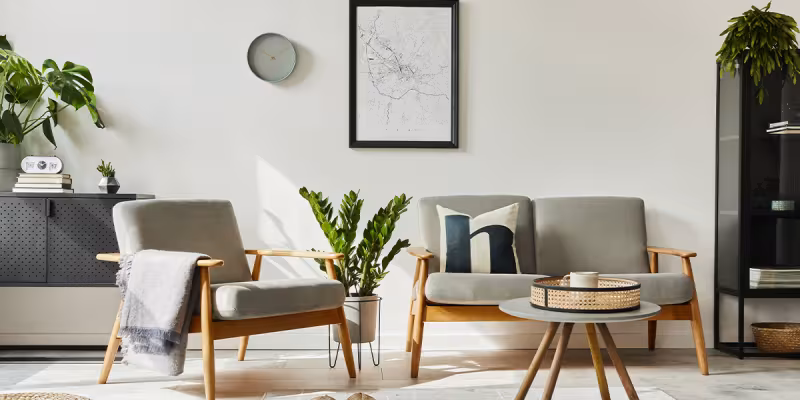 Soggiorno in stile scandinavo con poltrona e divano, piante e decorazioni su parete bianca
