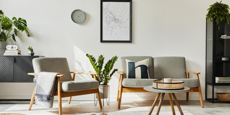 Soggiorno in stile scandinavo con poltrona e divano, piante e decorazioni su parete bianca