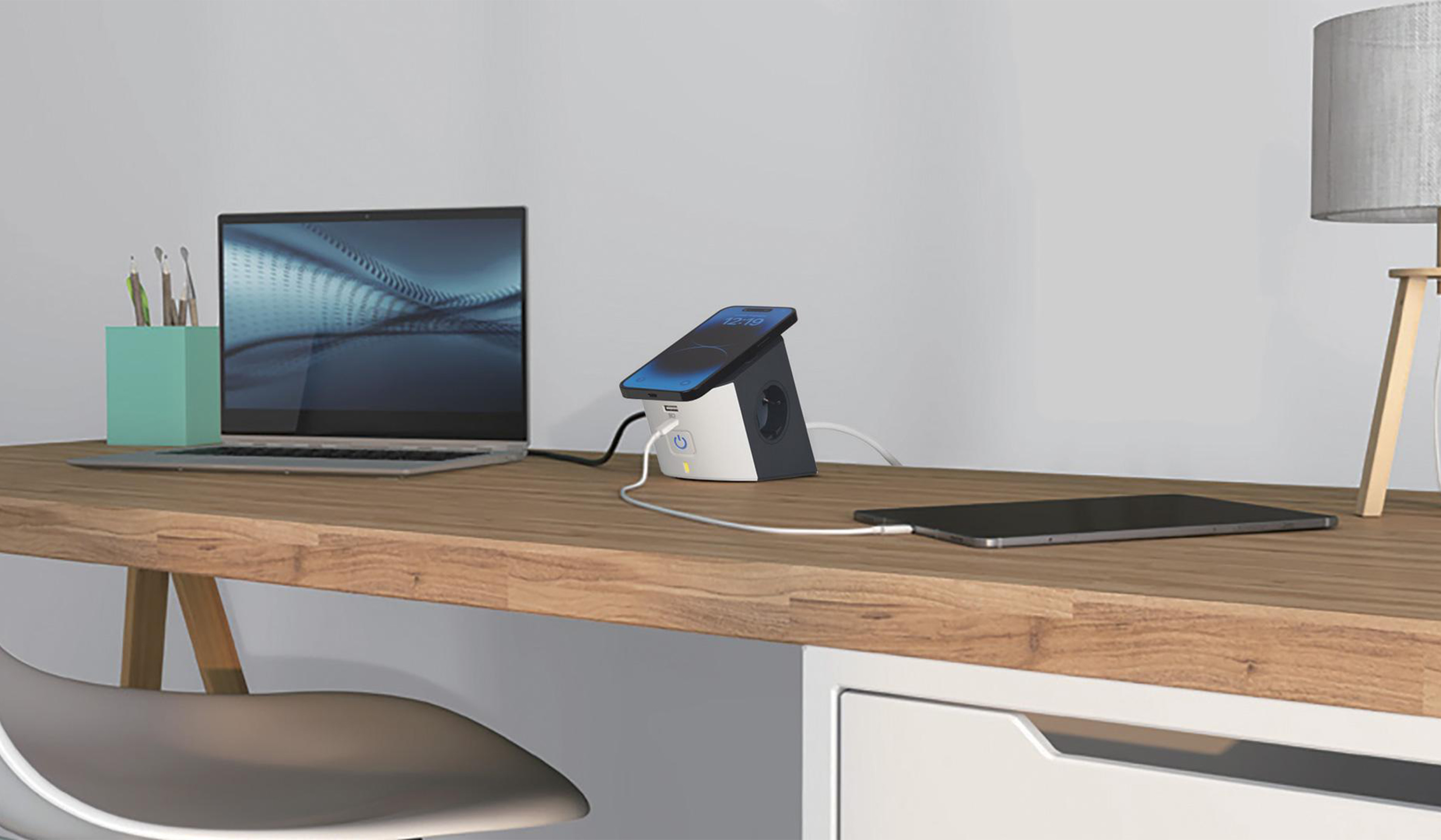 Scrivania con lampada, laptop e porta-penne; smartphone e tablet in ricarica tramite presa da scrivania con ricarica wireless BTicino